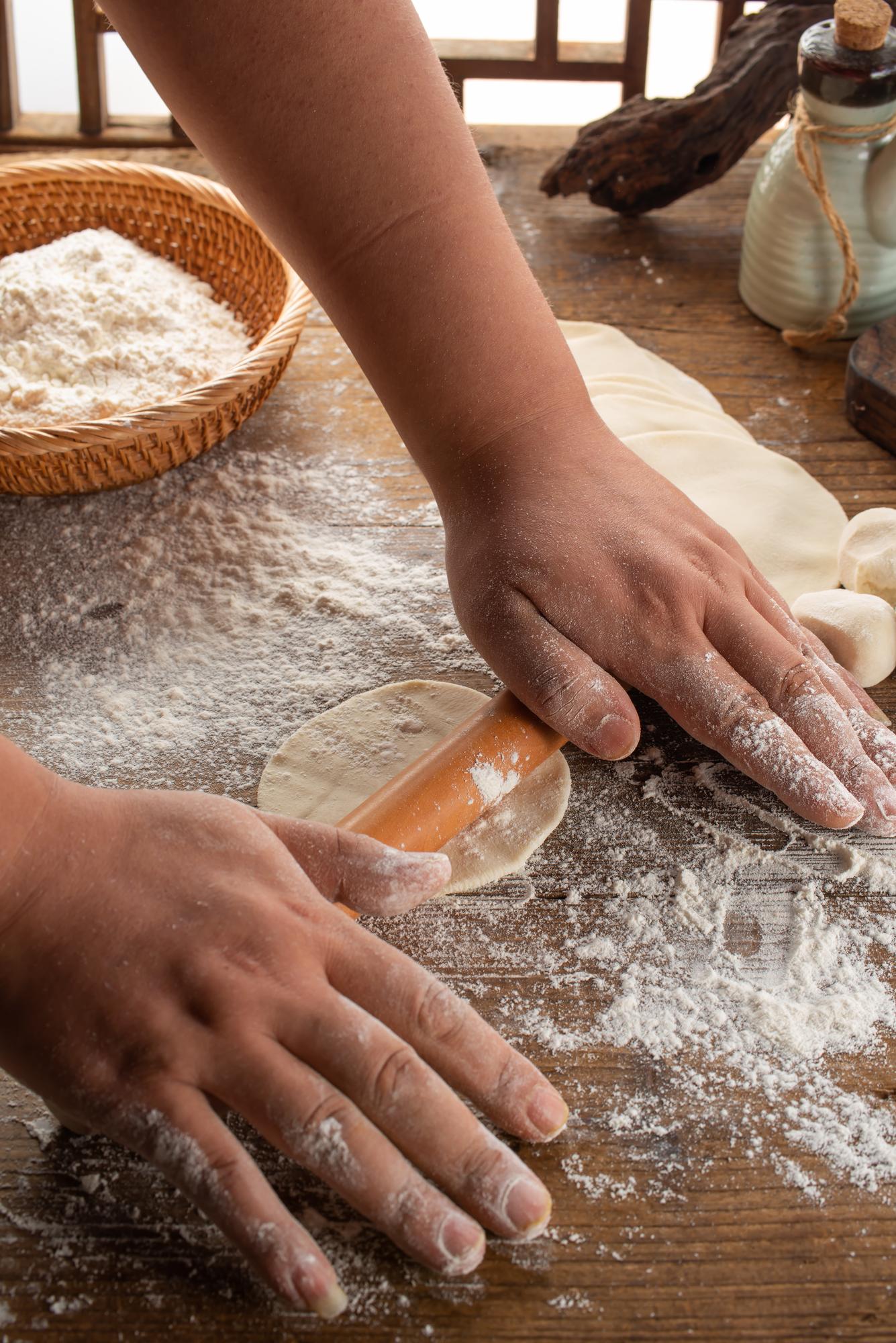 Hands kneading dough on floured board